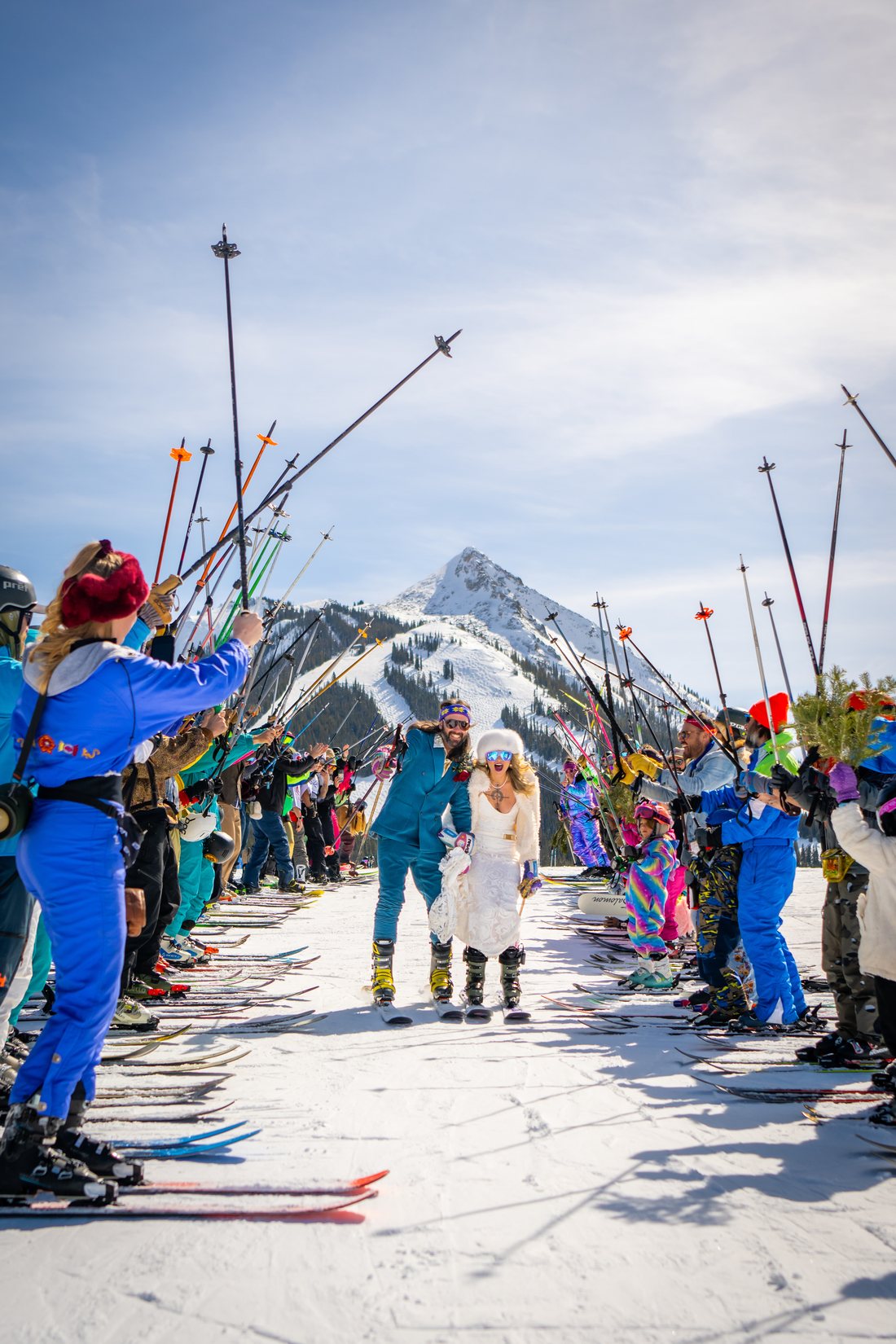 Janice and Alex skiing through an arch of ski poles held up by friends on their wedding day