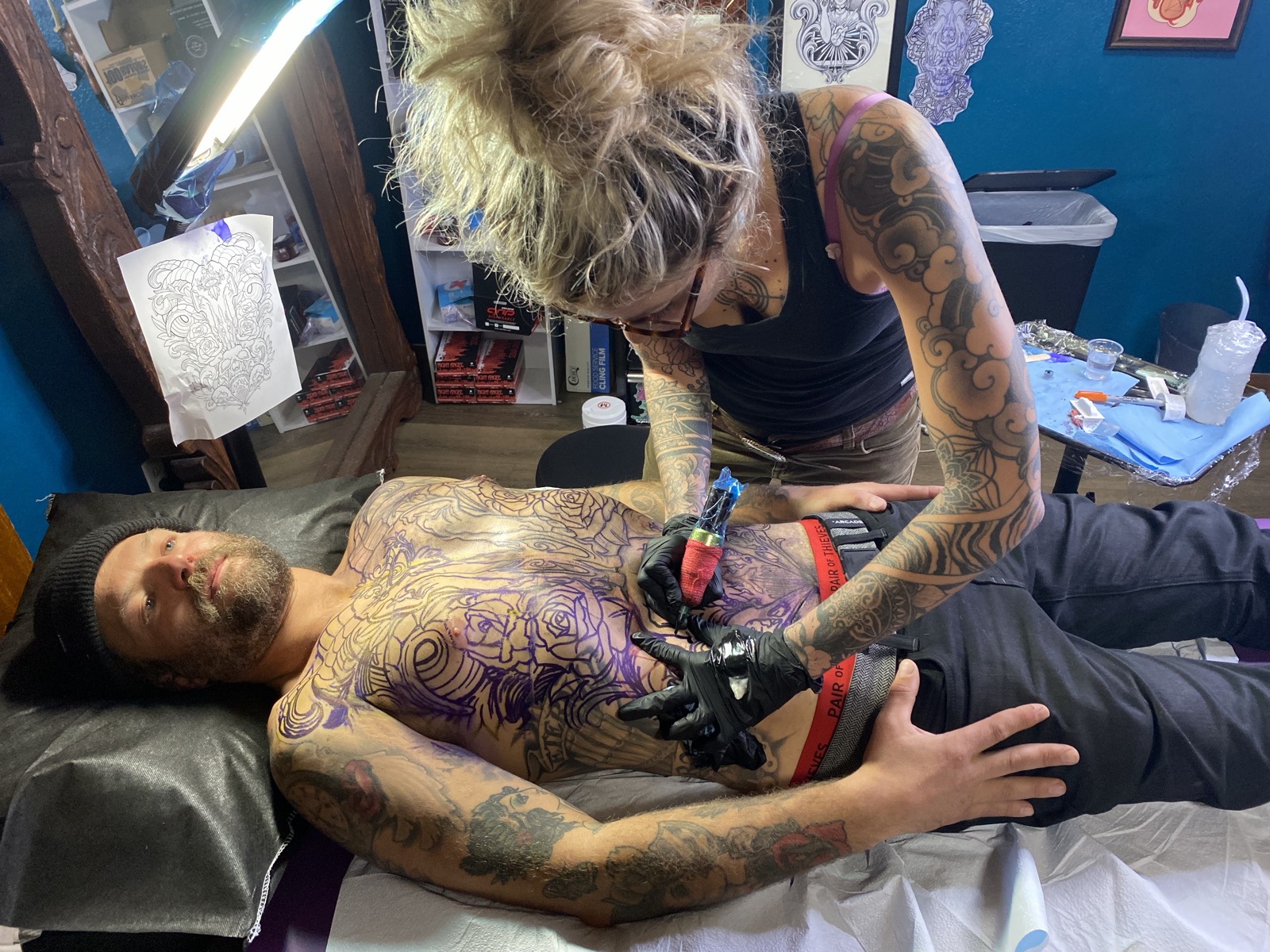 Janice tattooing a large chest piece on a reclining client