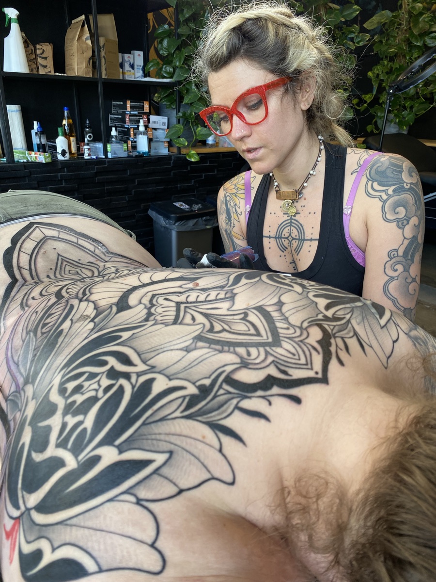 Janice working on a bold blackwork floral chest piece